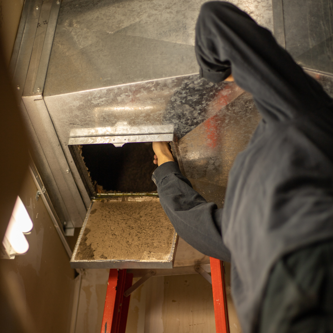 A Mighty Ducts employee works on an air duct